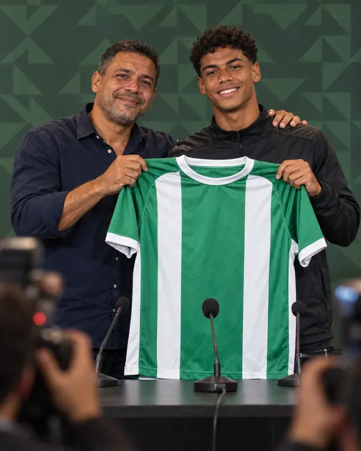 O mesmo pai, anos depois, ao lado do filho numa coletiva de imprensa de um clube, os dois sorrindo